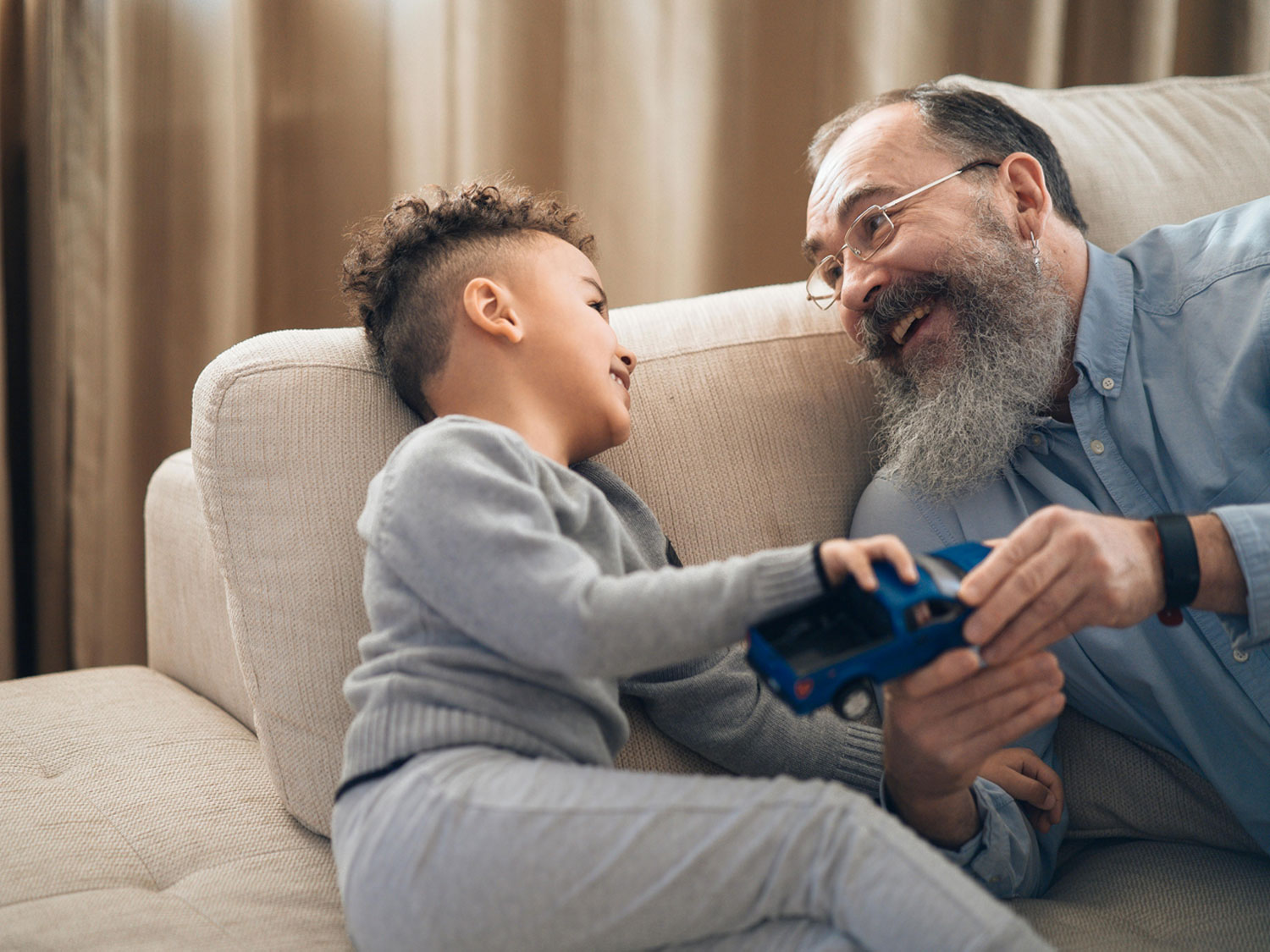 An image of a father and son playing with a toy car.